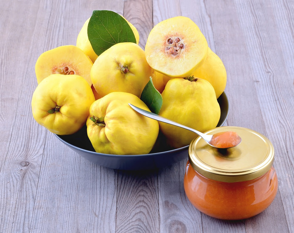 quinces with a leaf and jam on wood background